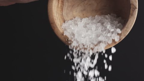 coarse sea salt crystal falling from bowl on black background in slow motion, 180fps prores footage