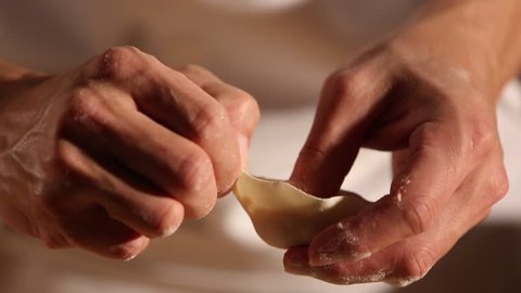 A chef is shaping the dough with meat inside to make dumplings. The chinese dumpling generally consists of minced meat and finely chopped vegetables wrapped into a piece of dough skin.