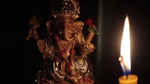 lord ganesha with candle burning on black background