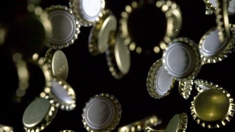 Bottle Caps in Flight. Golden beer bottle caps floating in the air on a black background. Slow Motion at a rate of 240 fps