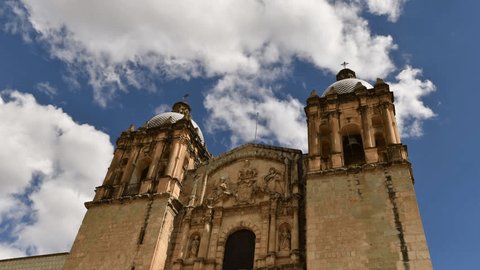 Cathedral of Santo Domingo in Oaxaca, Mexico, front of the church with two steeples and clouds that run behind the blue sky, time lapse
