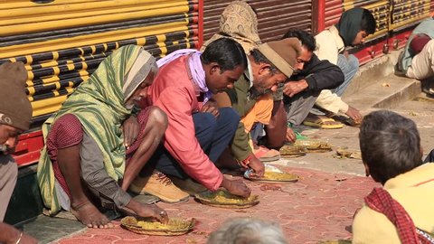 VARANASI, INDIA - JANUARY 25, 2017 : Unidentified poor indian people eating free food at the street near river ganges in Varanasi, India