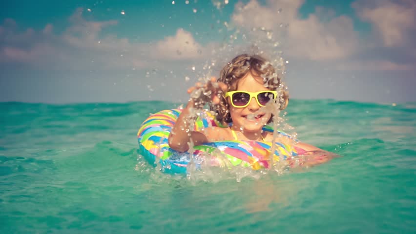 Happy child playing in the sea. Girl having fun outdoors. Summer vacation and holiday concept. Slow motion