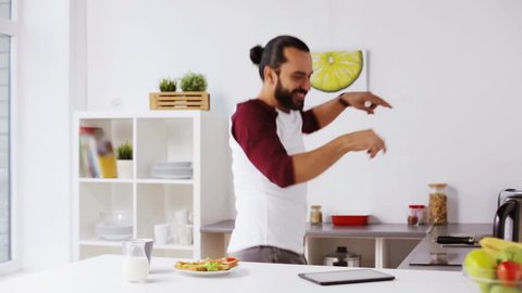 vegetarian food, healthy eating, people, technology and diet concept - man having sandwiches with coffee for breakfast and dancing to music playing on tablet pc computer at home kitchen