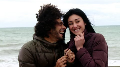 Happy couple playing in winter in front of the ocean