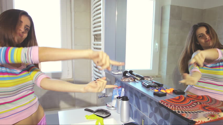 Happy succesful woman dancing in bathroom in front of mirror