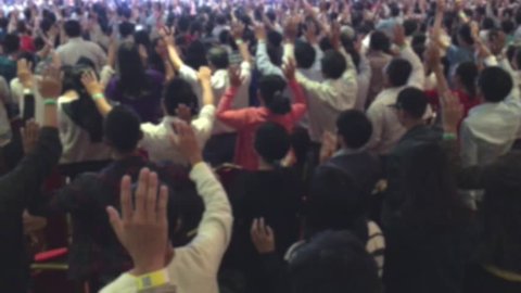 defocused view of people worshiping God with their raised hands