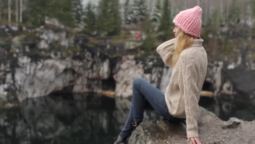 Karelia, Ruskeala. a Beautiful Young Girl Sitting on a Rock Cliff Near the Lake