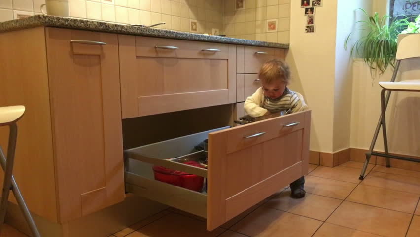 Baby boy playing with pots and pans on kitchen floor