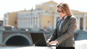 Elegant businesswoman working on her laptop outside in the city, copy-space provided