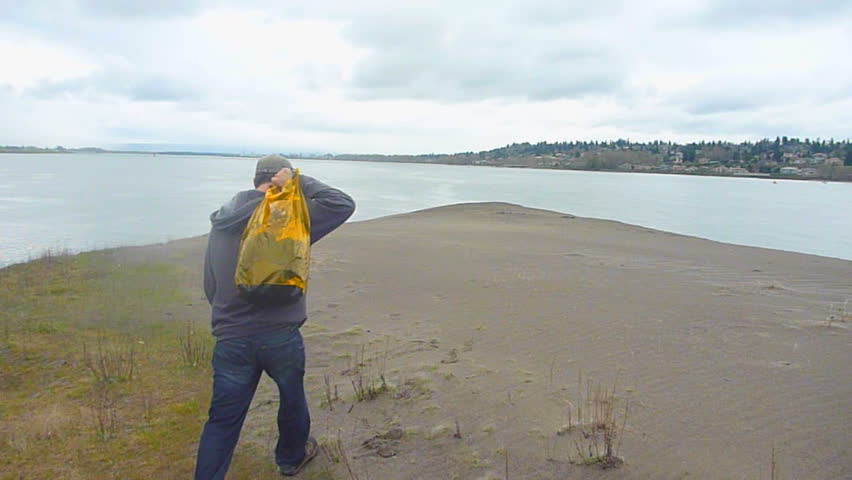 Man hiking away from camera towards Columbia River in Portland Oregon on a solo