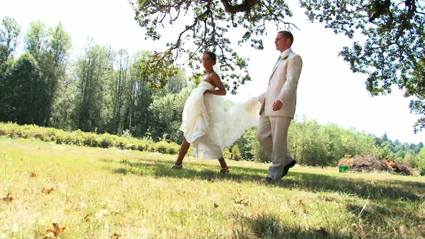 Bride and Groom walking together in field.