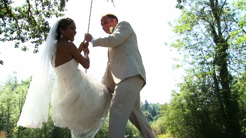 Bride and Groom play on swing at their wedding.