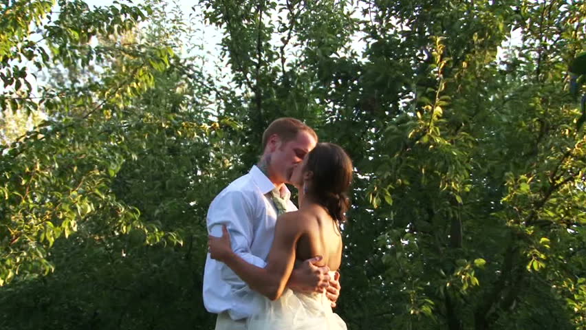 Bride and Groom after ceremony kiss outside in forest.