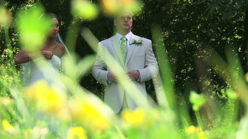 Bride and Groom stand in flower field getting ready for portraits.