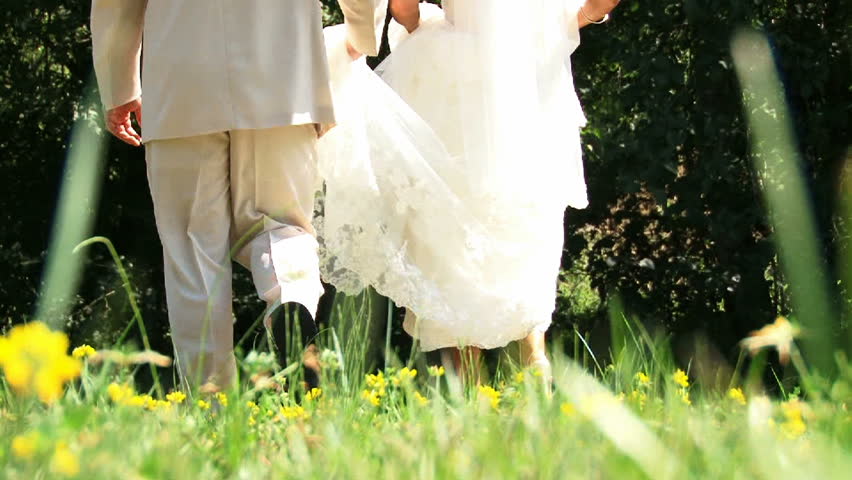 Bride and Groom walking together in flower field.
