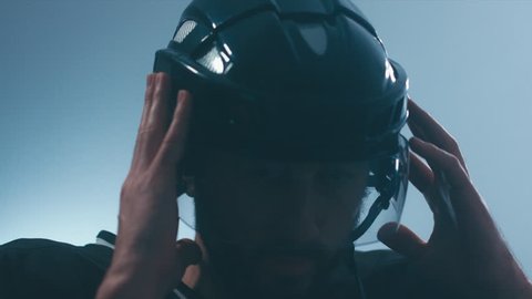 CU Portrait of Caucasian male ice hockey player in black uniform putting on his protective helmet in locker room, turning into camera. 4K UHD 60 FPS slow motion. RAW edited footage