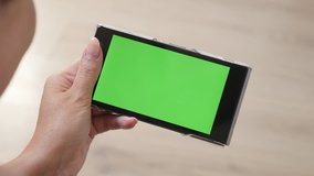 Modern female holds green screen mobile device 4K 2160p 30fps UltraHD footage - Surfing on Internet while lying on floor with greenscreen smart phone 3840X2160 UHD video