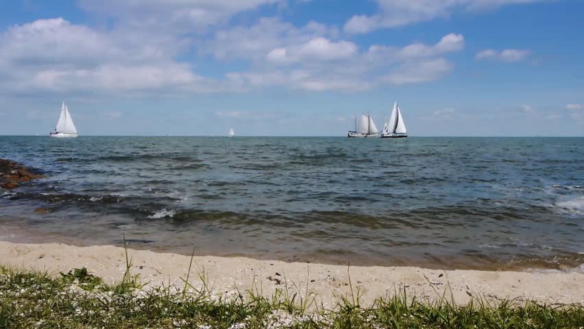 Scenic with seashore and sailing boats in the distance.