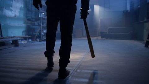Masked man with baseball bat walking in abandoned place. Shot on RED Cinema Camera in slow motion. 4K