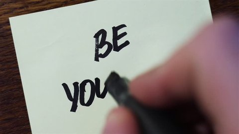 Be Yourself. Man Hand writing with black marker on paper.