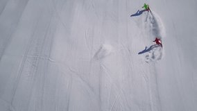 4k footage, top aerial drone view two skiers skiing on empty ski slope in clouds of snow