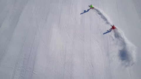 4k footage, top aerial drone view two skiers skiing on empty ski slope in clouds of snow