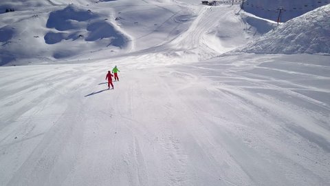 4k aerial footage, drone following two skiers on ski slope in skiing region