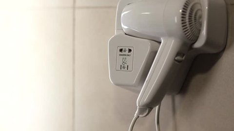 Hair dryer in bathroom. White hairdryer on the wall inside bathroom