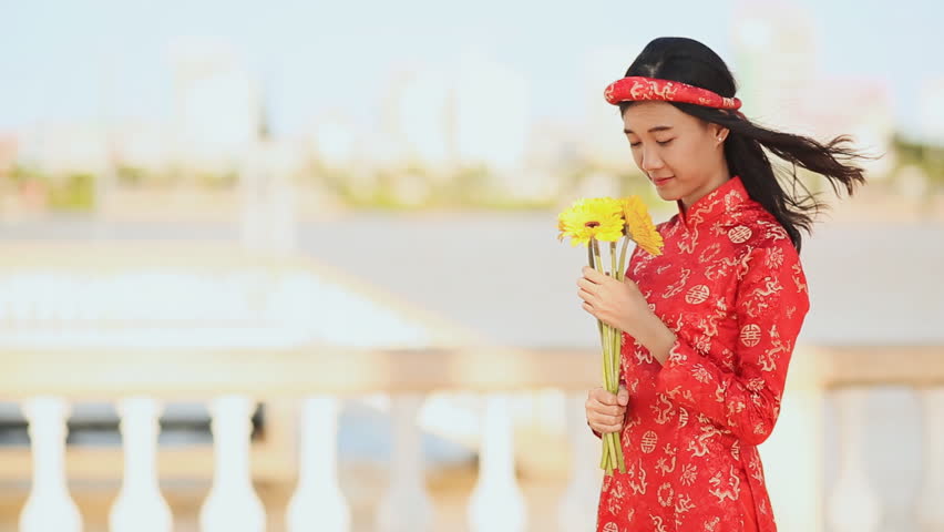 Beautiful Vietnamese girl in red traditional dress Ao Dai with yellow flowers.