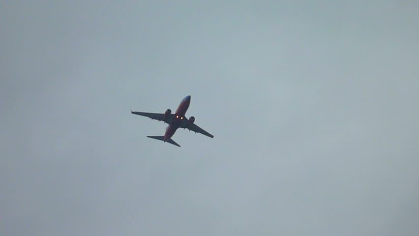 Airplane flying overhead on cloudy day.