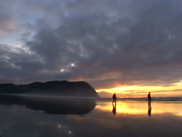 Two People Walking on Beach During Perfect Sunset in Seaside Oregon.