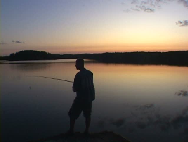 Man casts fishing in calm lake water in Minnesota. 
