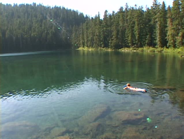 Woman on raft floating on Oregon lake during summer. 