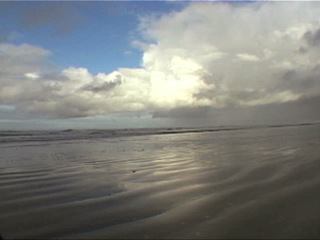 Close up Clouds build in time lapse, pull out to wide clouds with man on beach walking by in Seaside, Oregon