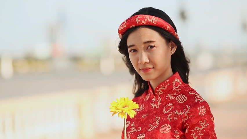 Beautiful Vietnamese girl in red traditional dress Ao Dai with yellow flowers.