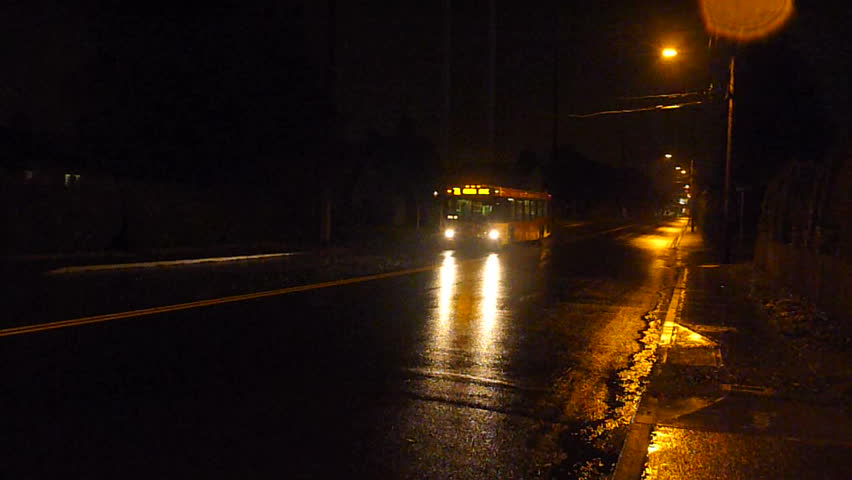 City bus drives at night in rain storm.