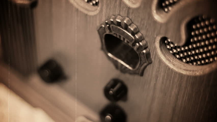 Turning an old-fashioned radio.  Shallow DOF.  Old, scratchy film look.