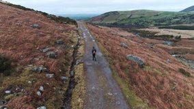 Aerial Drone Of Hiker Walking On Dirt Road Amidst Landscape