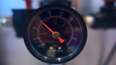 Black gauge with red arrow indicate surges of pressure in the system of industrial equipment
