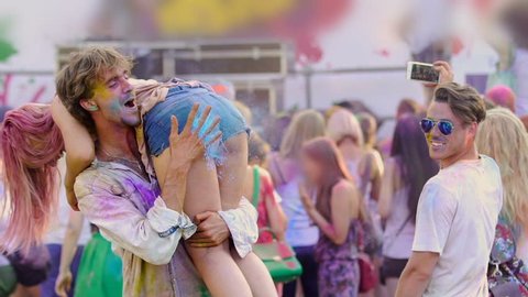 Excited boyfriend spanking girlfriend at Color festival, young people having fun