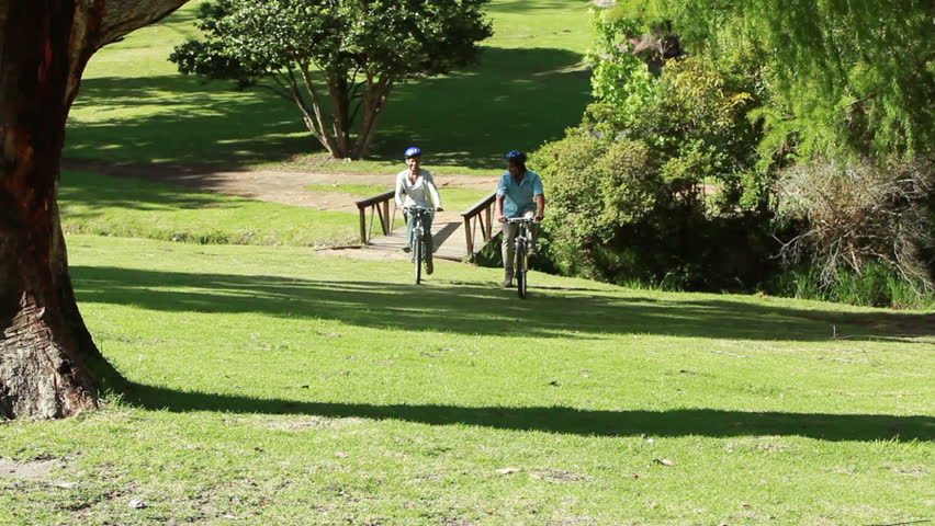 Happy couple riding their bikes together in a park