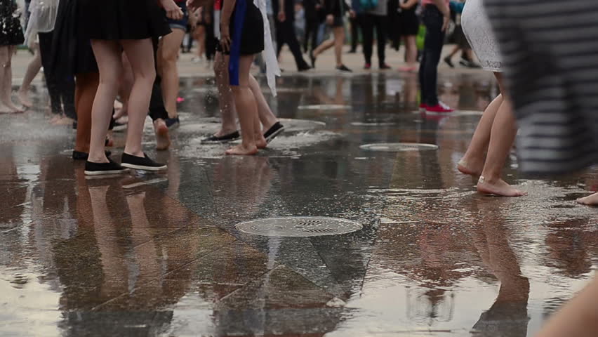 Closeup of youg people's legs running on puddles in park