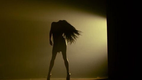 Beautiful dancer demonstrating her perfect sensual figure and dancing on dark brown background with strobe light effect . Shot on RED HELIUM Cinema Camera in slow motion.