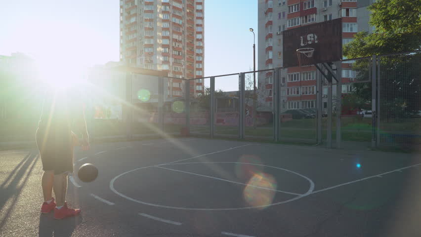 Guy successful throws a ball in a basket adult male wearing in sportswear early morning.