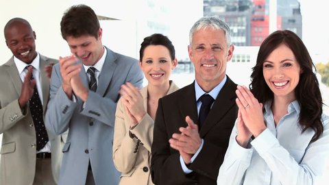 Happy business team applauding together in a bright room