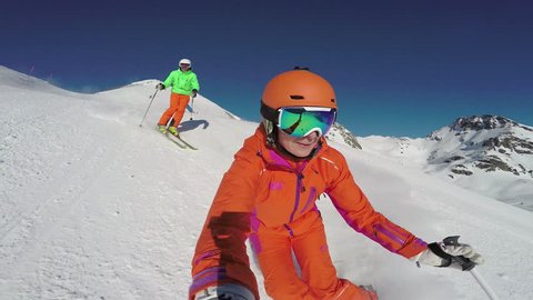 4k skiing footage, woman filming selfie point of view with two skiers following her down ski slope