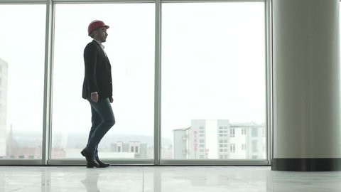 Handsome architect man walking in new building in front of panoramic windows 