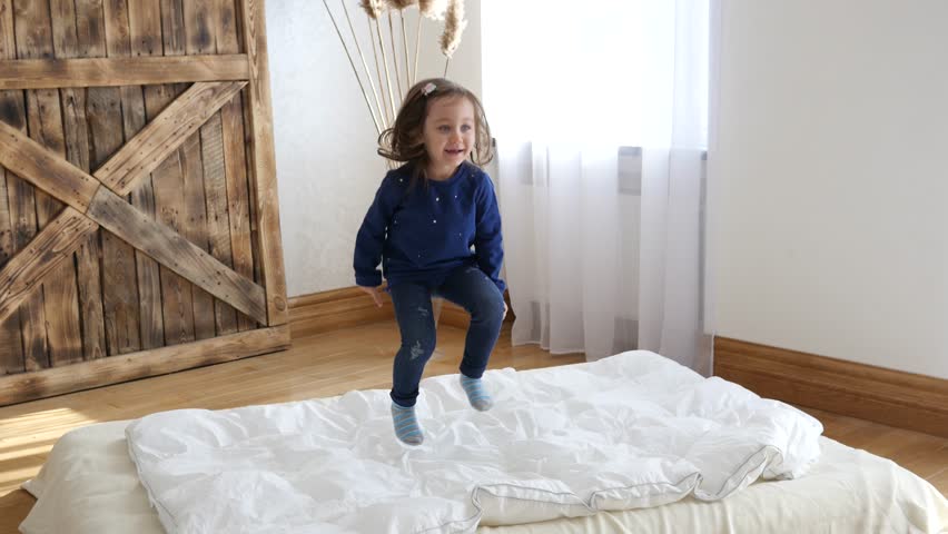 Happy Childhood Active Little Cute Girl Have Fun Jumping On A Bed