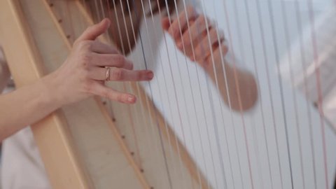 Hands of woman playing a harp. Harpist with classical music instrument. Harp strings close up.